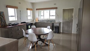 A modern kitchen with a dining table, chairs, and a large window.
