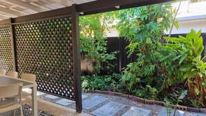 A covered patio area with a lattice partition, a table with chairs, and a patterned rug. - Seaestaatmoffatquietbeachparklargefenced Yard (Sunshine Coast)