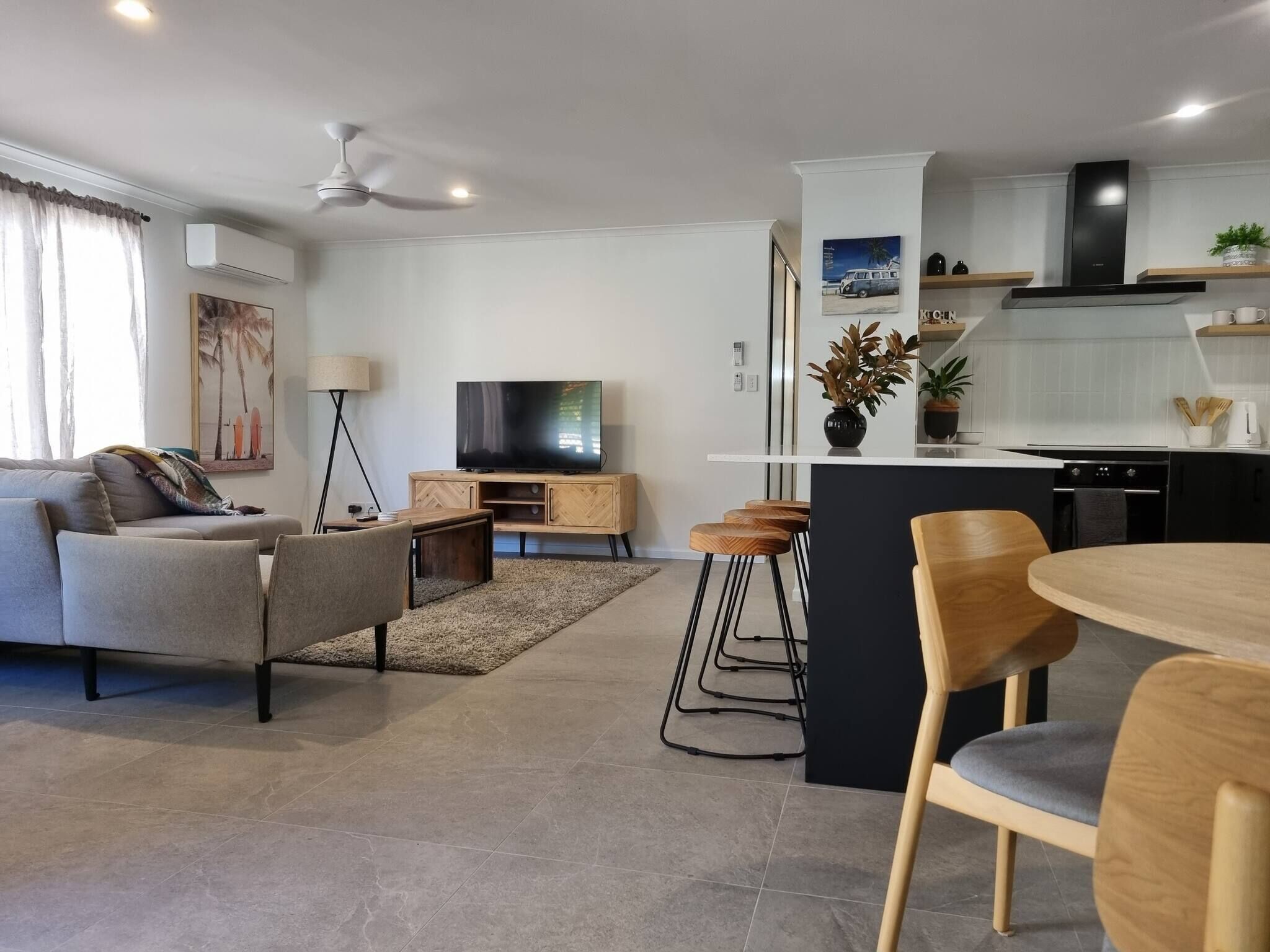 A modern living room with a sofa, TV, and a dining area with chairs and a table.