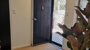 A dog lying on a doormat in front of a dark door with a metal gate. - Seaestaatmoffatquietbeachparklargefenced Yard (Sunshine Coast)