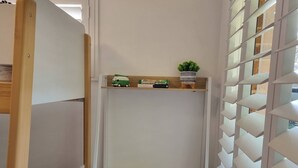 A compact workspace with a white desk, a white chair, and a shelf with a plant and books. - Seaestaatmoffatquietbeachparklargefenced Yard (Sunshine Coast)