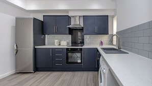 A modern kitchen with dark cabinets, a stainless steel refrigerator, a built-in oven, and a dishwasher. - Apartment - Sleeps 7 - Parking - Close to Pier (Clacton-on-Sea)