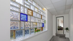 A hallway with a large window featuring colorful glass panels and a small plant on the windowsill. - Apartment - Sleeps 7 - Parking - Close to Pier (Clacton-on-Sea)