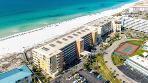 Een kusthotel met meerdere gebouwen, een strand en een tennisbaan.
