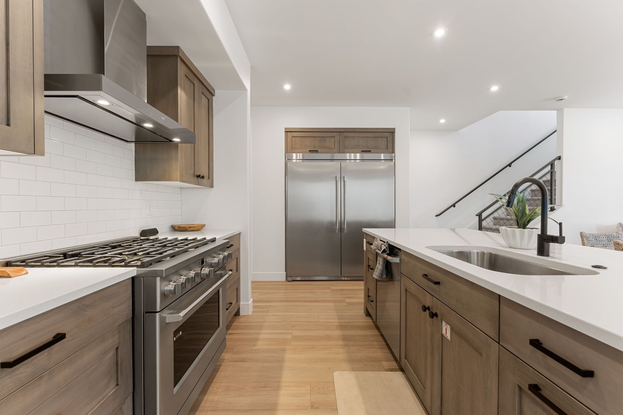 A modern kitchen with stainless steel appliances, wooden cabinets, and a white countertop.