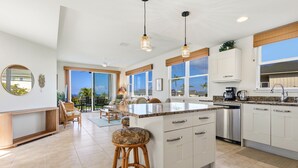 A spacious kitchen with a large island, white cabinetry, and a view of the outdoors. - Big Island Na Hale O Keauhou C5 2 Bedroom Condo (Kailua-Kona)