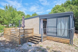 Eine kleine Holzhütte mit Balkon und einer Schiebetür aus Glas.