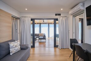 A modern living room with a sofa, a dining table, and a view through a glass door to an outdoor balcony. - MH Holiday Dream - Silver Moon - Oaza Mira Campsite (Drage)