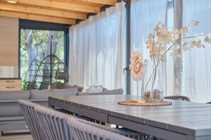 A modern dining area with a wooden table, wicker chairs, and a vase with dried flowers. - MH Holiday Dream - Silver Moon - Oaza Mira Campsite (Drage)