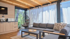 Een modern interieur met een bank, een hangstoel, een koffieapparaat en een televisie.