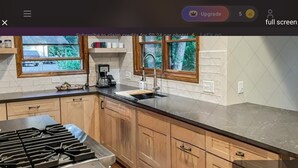 Een keuken met houten kastjes, een zwart aanrecht, een fornuis en een koffiezetapparaat.