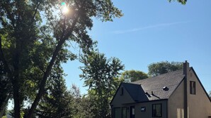 Ein Wohnhaus mit geneigtem Dach, einem gepflegten Rasen und einem Bürgersteig.