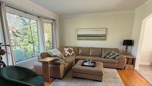 Ein modernes Wohnzimmer mit einem Ecksofa, einem grünen Sessel und einem Couchtisch.