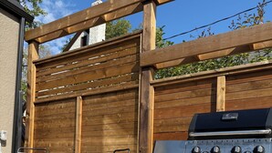 Eine Terrasse im Freien mit Grill, Stühlen und Tisch.