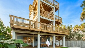 A two-story wooden house with a balcony, a patio with outdoor furniture, and a well-maintained lawn. - Oceanview Rooftop Retreat | Steps from the Beach (Jacksonville Beach)