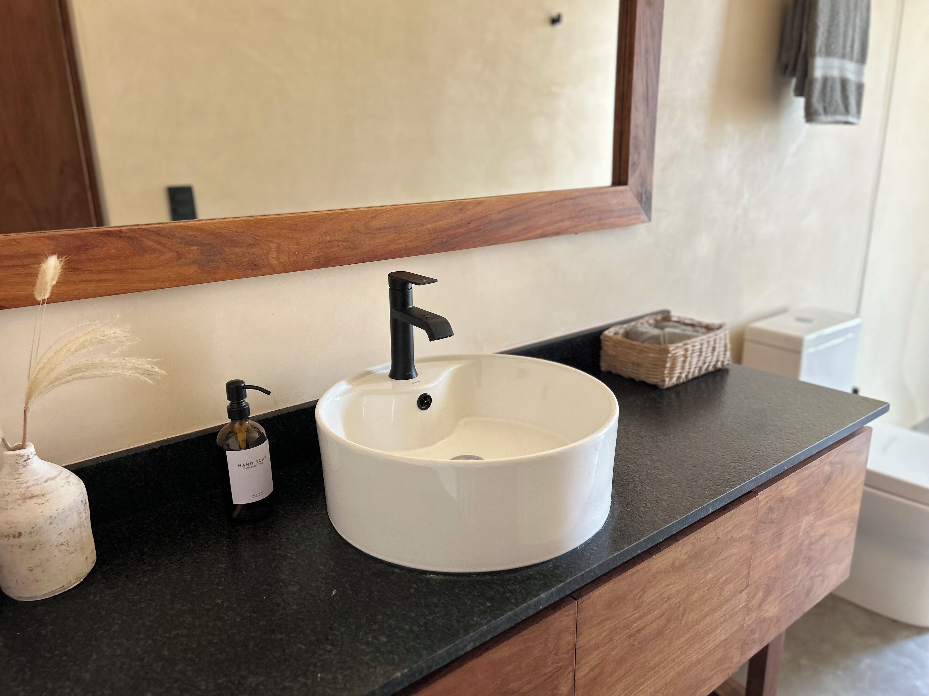 A bathroom with a white sink, black faucet, and a mirror above it.