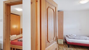 Une pièce avec une armoire en bois, un lit avec un matelas rouge et un plancher en bois.
