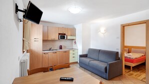 Un espace de vie compact comprenant un coin cuisine, une table à manger, un canapé et un lit.