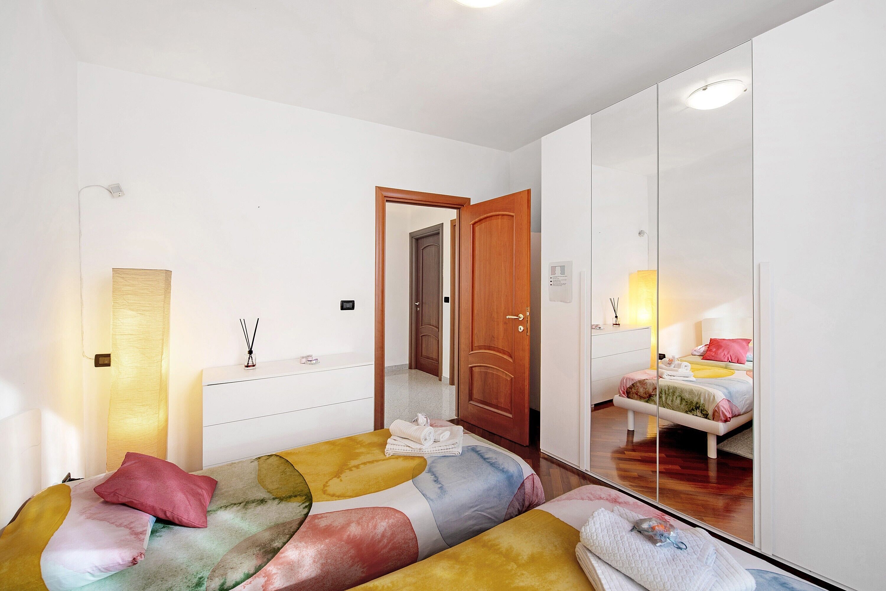 Un dormitorio con cama, cómoda, espejo y puerta que da a otra habitación.