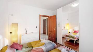 Un dormitorio con cama, cómoda, espejo y puerta que da a otra habitación.