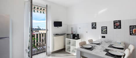 A modern kitchen with a dining area, a TV, and a view of the city.
