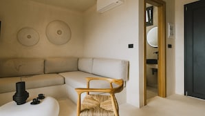 Uma sala de estar moderna com um sofá seccional, uma cadeira de madeira e uma mesa pequena com um vaso e xícaras.