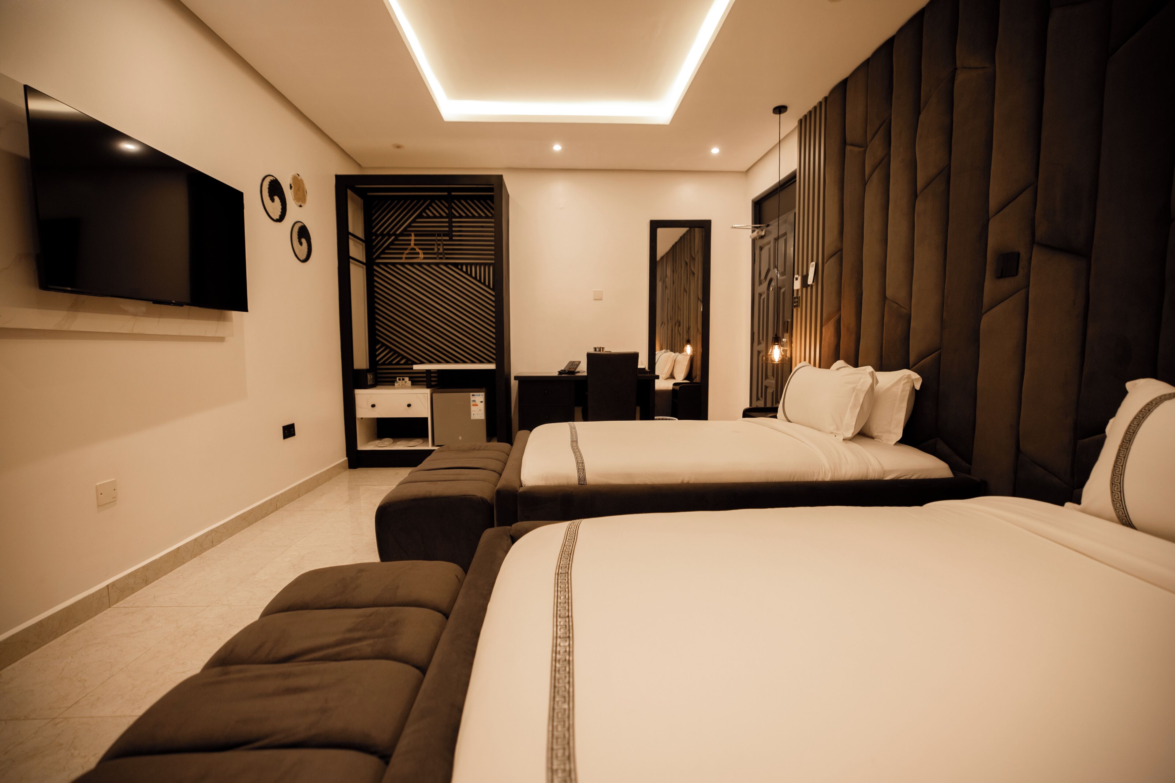 A hotel room with two beds, a flat-screen TV, a desk, and a wardrobe.