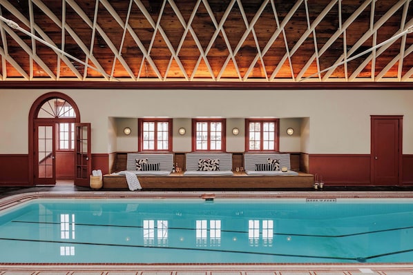 Une piscine avec un plafond en bois, un banc avec des serviettes et une porte.