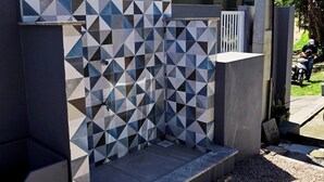 Et moderne udendørs bruseområde med geometriske flisemønstre og en betonkonstruktion.