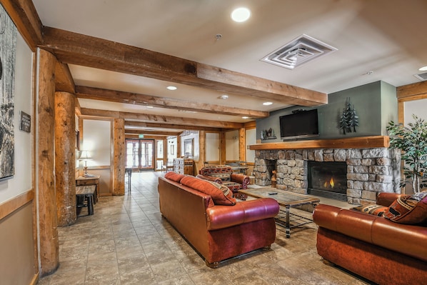 A spacious living area with a stone fireplace, leather sofas, and wooden beams. - Poolside Perfection| Updated | River Run Village (Keystone)