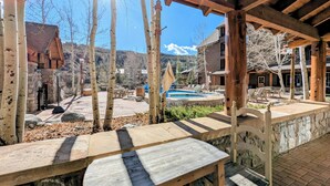Eine Holz-Pergola mit einer Steinsitzbank, die auf einen Poolbereich mit Liegestühlen blickt.