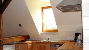 Eine Küche mit Holzschränken, einem Fenster, einer Spüle und einem Herd.