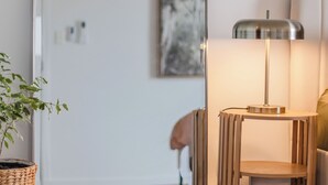 A modern room with a standing lamp, a potted plant, and a piece of abstract art on the wall. - Layback on Marine (Kingscliff)