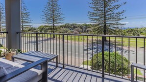 A balcony with a view of a road, trees, and a clear sky. - Layback on Marine (Kingscliff)