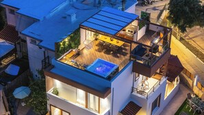 Ein modernes, zweistöckiges Haus mit Pool auf dem Dach, Essbereich und kleiner Küche.
