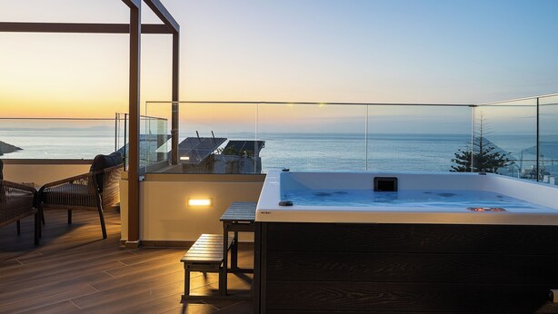 Eine moderne Dachterrasse mit Whirlpool, Sitzgelegenheit und Blick auf den Ozean.