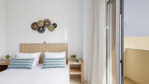Ein Schlafzimmer mit einem Bett, zwei Nachttischen, einem Wandbild und einer Glastür zum Balkon.