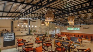Un vaste espace intérieur aménagé avec différents coins salon, comprenant des canapés et des fauteuils, ainsi qu’une grande table à manger centrale, dressée avec des plats.