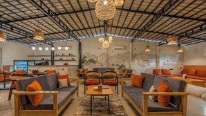Un vaste espace de détente avec des canapés et des fauteuils, une table basse centrale et des lampes suspendues en osier.