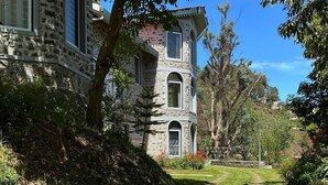 A stone building with arched windows and a pathway leading to it. - Whispering Palms Kodaikanal (Kodaikanal)