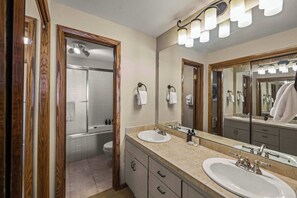 A bathroom with two sinks, a large mirror, and a shower. - The Plaza 231 | Walk to CBMR Lifts | 2BR Sleeps 6 (Crested Butte)