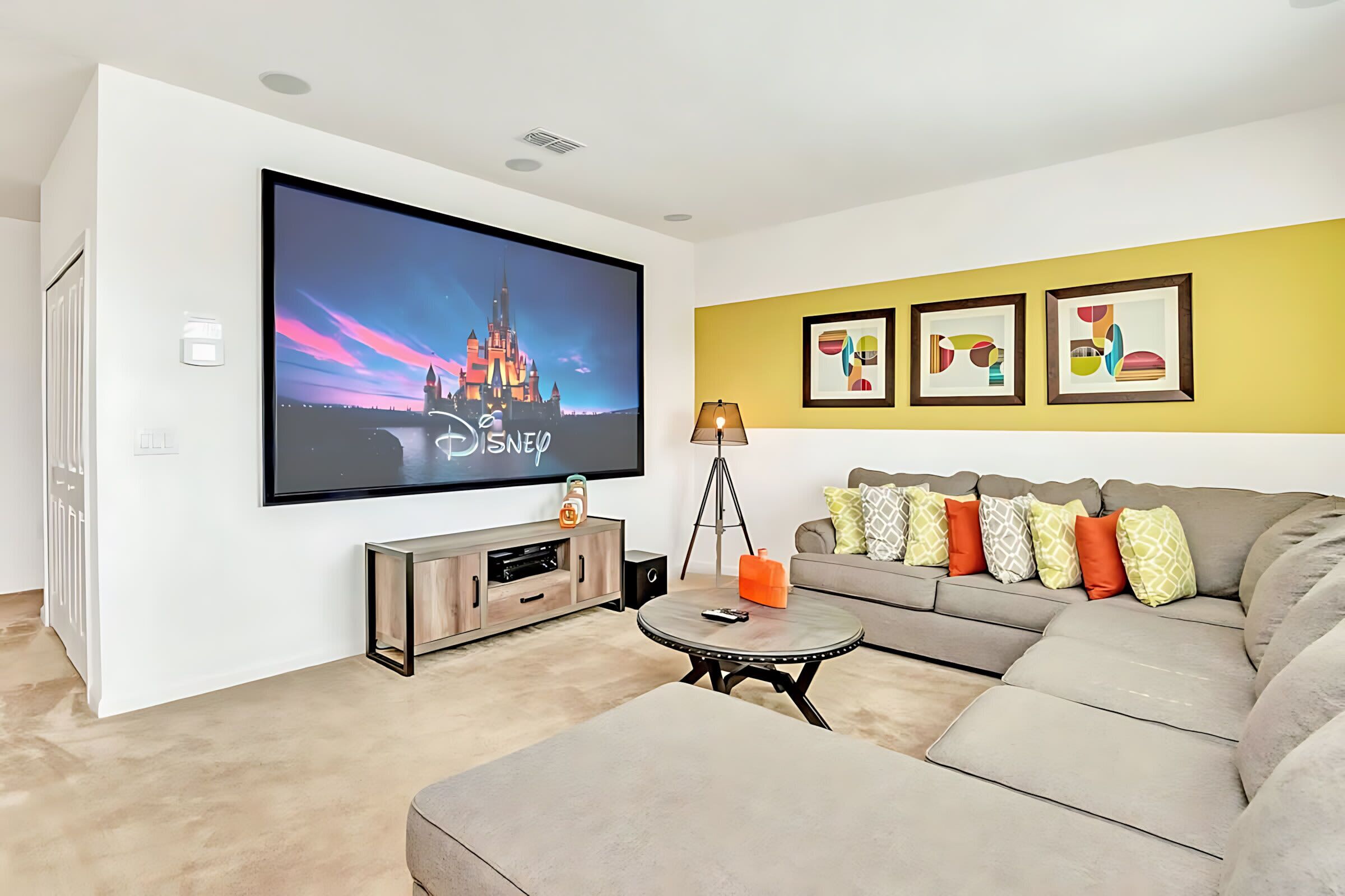 A modern living room with a flat-screen TV, a sofa, a coffee table, and framed artwork on the wall.