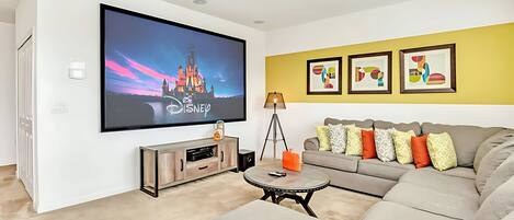 A modern living room with a flat-screen TV, a sofa, a coffee table, and framed artwork on the wall.