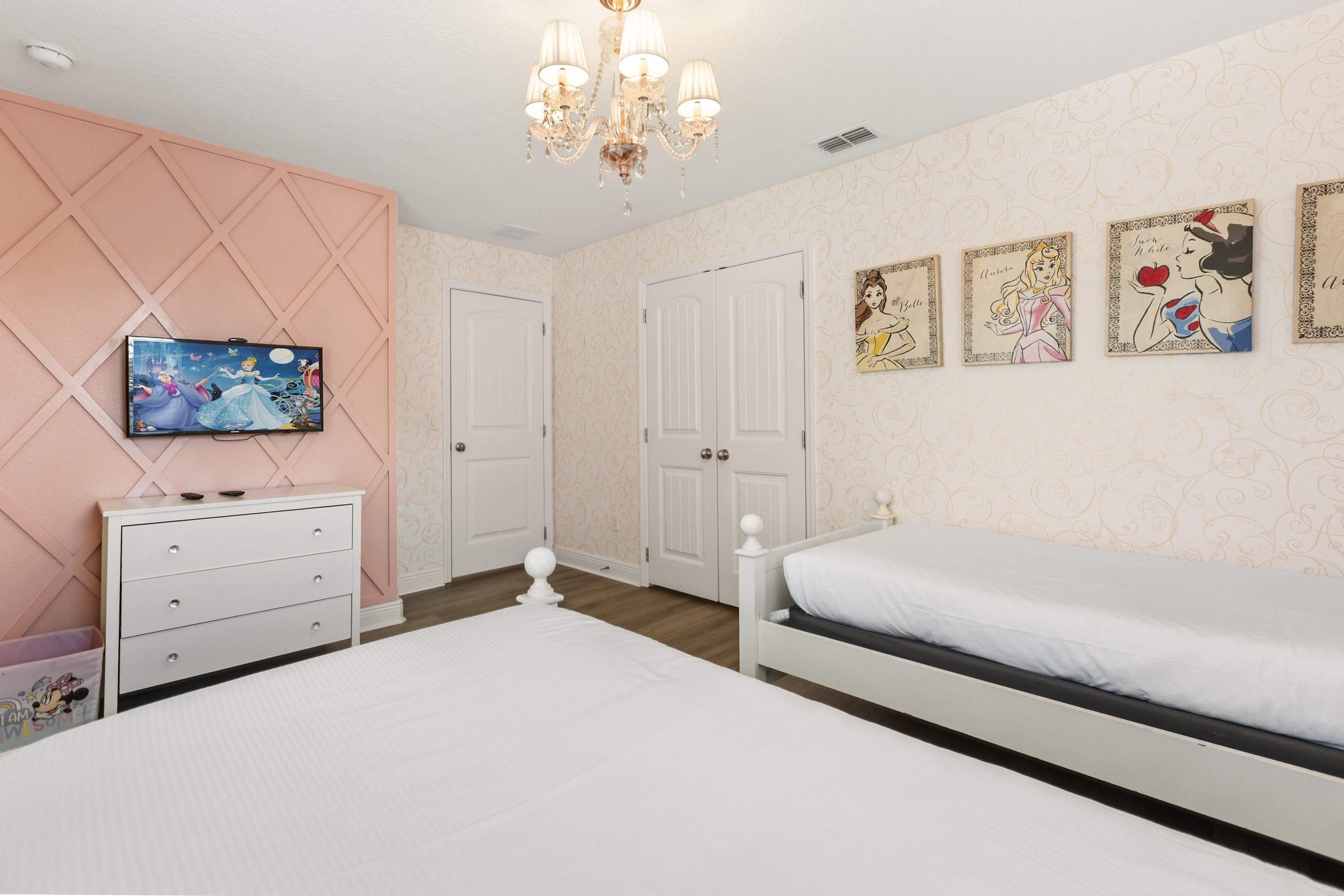 A bedroom with a bed, dresser, television, and wall art.