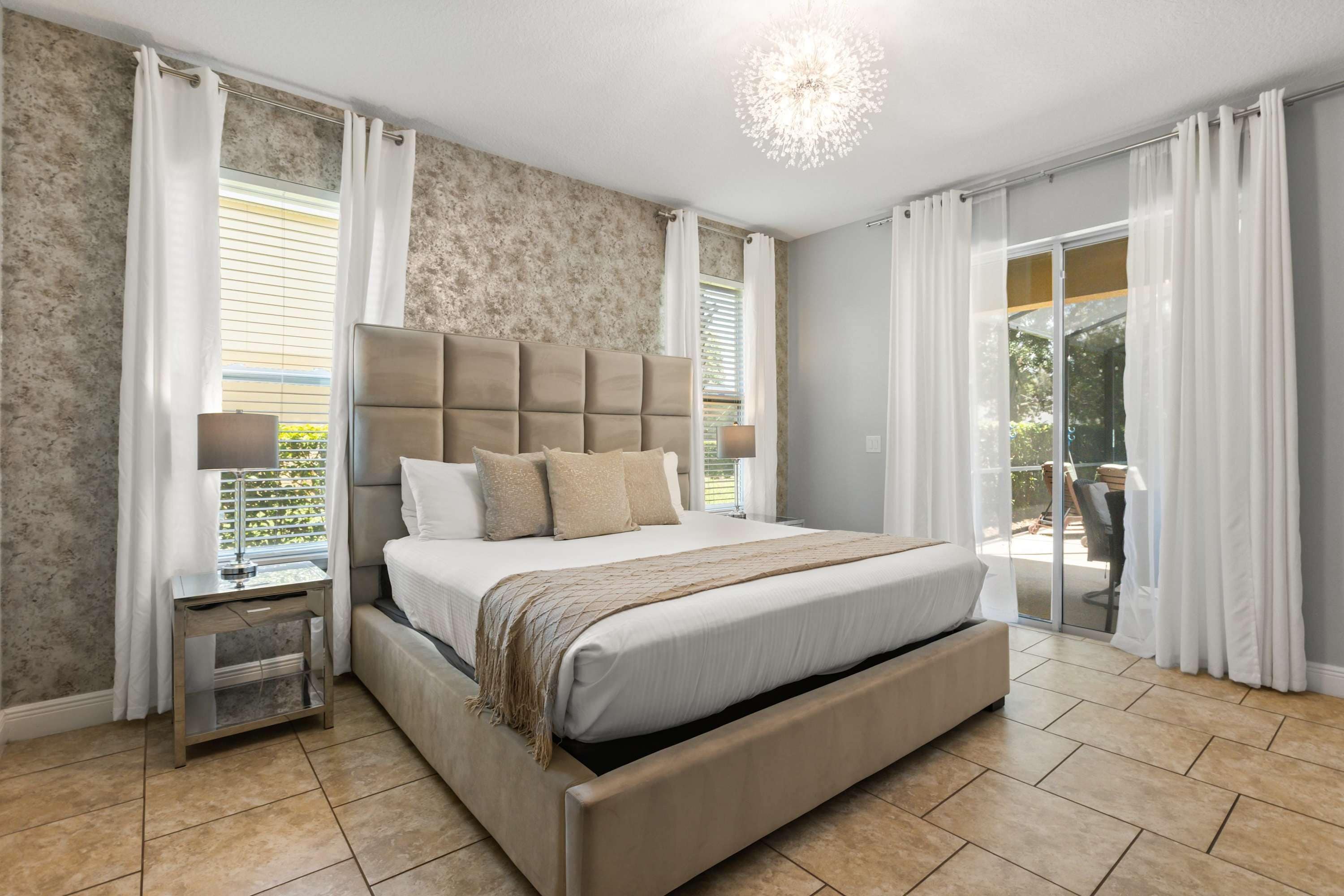 Una camera da letto con un letto grande, un comodino, una lampada e vista sull'esterno tramite una porta scorrevole in vetro.