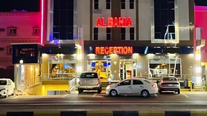 Un hotel con una zona de recepción y varios coches aparcados delante.
