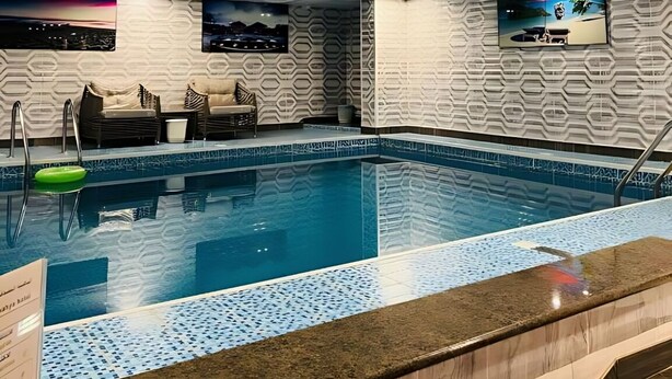 Una piscina con borde alicatado, un techo con iluminación empotrada y una pared con diseño.