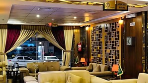 Un hall de hotel con diseño moderno, que incluye una zona de estar con sofás y sillones, una pared decorativa y un cartel que indica la zona del hall.