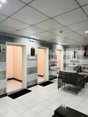 Un baño moderno con suelo de baldosas, un banco negro y un espejo sobre el lavabo.