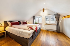 Una camera da letto con un letto grande, un comodino, una finestra con tende e vista sugli edifici.